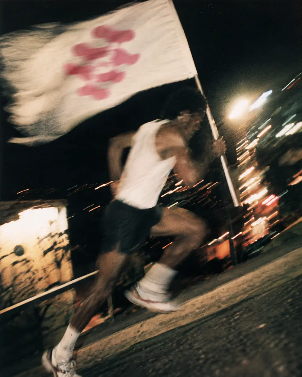 Corredor segurando uma bandeira, à noite, em movimento